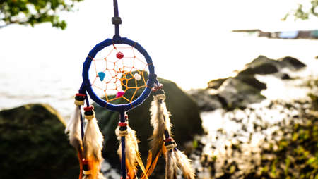 Dreamcather with sunset sea view background.,  Native american dream catcher. boho chic, ethnic amulet.の写真素材