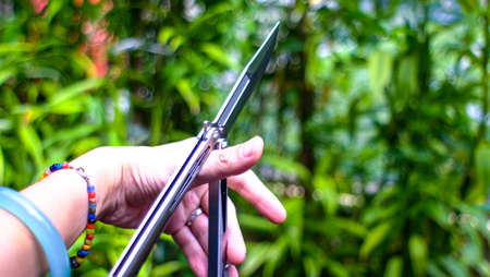 Butterfly knife (balisong) in female hand on a nature backgroundの写真素材