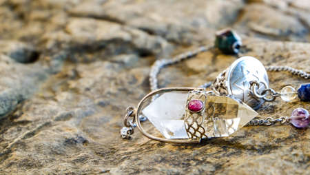 holding and using quartz crystal pendulum and using it In asking questions. pendulum quartz on stone...