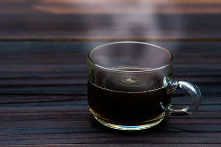Transparent cup of coffee placed on dark  on wood background.の写真素材