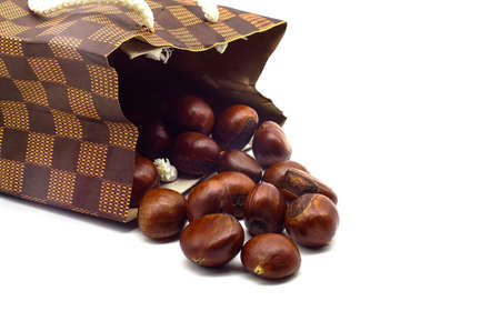 Ripe chestnuts in paper bag isolated on white background close up with copy space. Roasted Chestnuts for Christmas.の写真素材