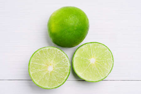 Natural fresh lime and sliced, green leaf isolated on white wooden background.の写真素材