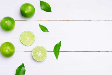 flat lay natural fresh lime with whole and cut lime slices, green leaf on white wooden table background. top view.の写真素材