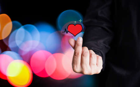 Mini heart hand on bokeh Night background. male finger making symbol small heart. Valentine lover.の写真素材