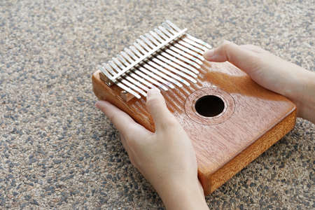 Woman holding play thumb piano or kalimba musical instrument.  play on hands and plucking the tines...