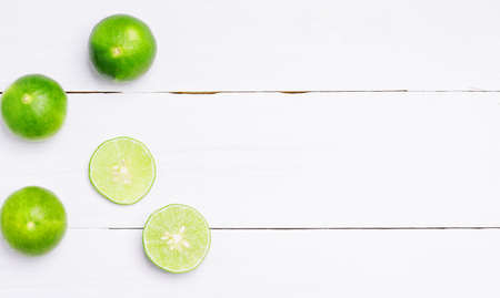 flat lay natural fresh lime with whole and cut lime slices, green leaf on white wooden table background. top view.の写真素材
