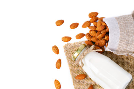 Top view glass bottle of milk with almond in hemp fabric bag isolated on white background. Homemade almond milk and clipping paths. healthy food.の写真素材