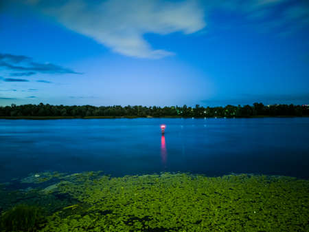 The buoy glows red and denoting the fairway at night in the middle of the riverの写真素材