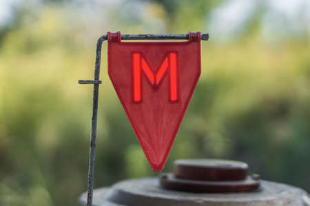 Red plastic minefield pointer with a red glowing letter "M" with a mine in the background.の写真素材