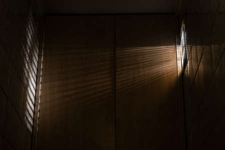 Contaminated ventilation hole, through the grille of which light with a striped shadow penetrates into a small room.の写真素材
