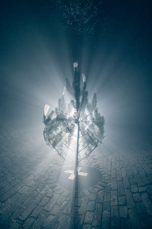 Silhouette of a Christmas tree in the fog, decorated with medical masks in the sewer tunnel.