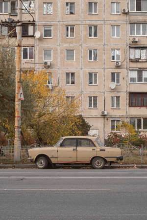 Beige retro car Moskvich-412 on the street with an old Soviet prefabricated house of beige color in the background. The concept of Soviet everyday life. Kyiv, Ukraine - October 2021.のeditorial素材