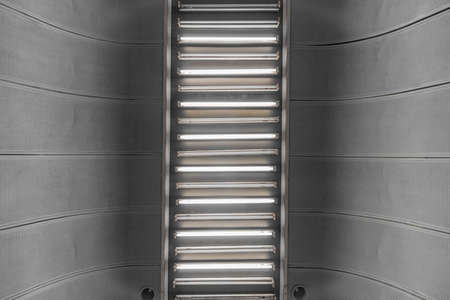 A row of elongated fluorescent lamps on the ceiling in modern interior.