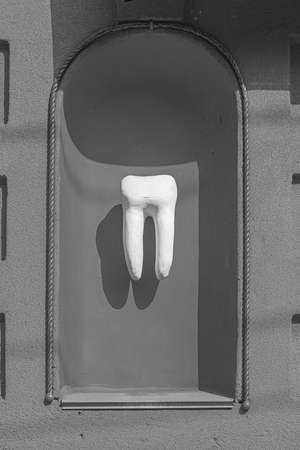 Sculpture of a healthy human tooth in the facade of the house.