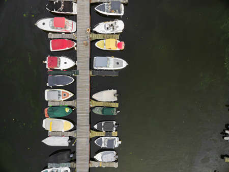 Top view of the boat dock with a wooden bridge and various boats. on the water surface, drone view. Kyiv, Ukraine - August 2021のeditorial素材