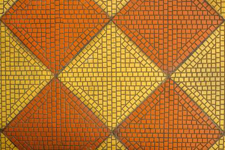 Old vintage mosaic tile of the 19th century in the shape of diamonds of orange and red colors, close up.の写真素材