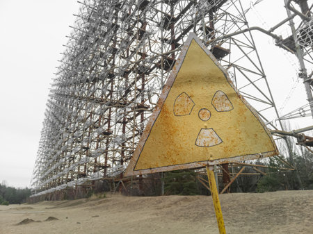 Faded sign of radiation threat against the background of an abandoned antenna of a horizon radar...