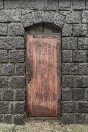 Ancient stone arch with a rusty metal door.の写真素材