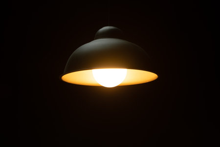 Warm orange LED lamp in the ceiling on a dark background in the center of the frame, bottom view.