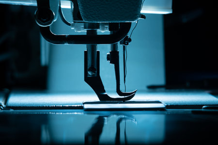 The silhouette of the needle with thread in the sewing machine is illuminated by cold backlight.