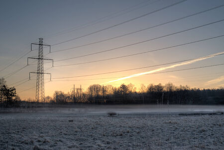 Power lines hanging over a misty meadow  It is an early morning in the early spring  The sun has just begun rising の写真素材