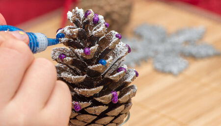 Girl making home made Christmas decoration out of a spruce cone の写真素材