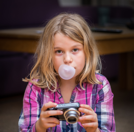 Tired young girl with camera and bubblegumの写真素材