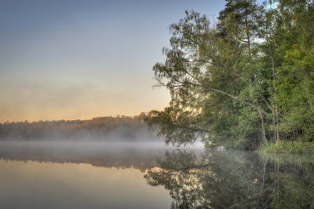 Dawn and fog drifting across the lakeの写真素材