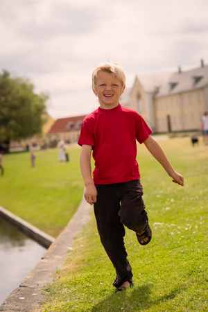 Boy running by water edge in a park with people in the backgroundの写真素材
