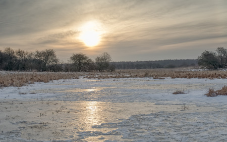 Sunrise over a frozen meadow in early spring.の写真素材