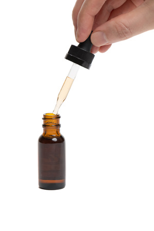 Brown glass bottle with straight dropper held by personの写真素材