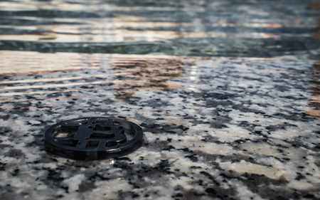 Plastic black bit coin on stone surface with water background.の写真素材