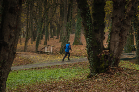 Running men in the park during fall and cloudy dayの写真素材