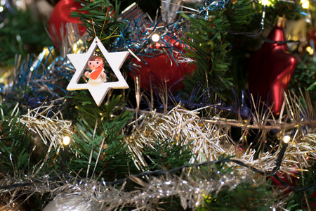 Artificial christmas tree decorated with wooden figurine, decoration for christmas tree, lights, tinsel and garland, red ballsの写真素材