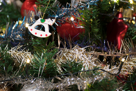 Artificial christmas tree decorated with wooden figurine, decoration for christmas tree, lights, tinsel and garland, red ballsの写真素材