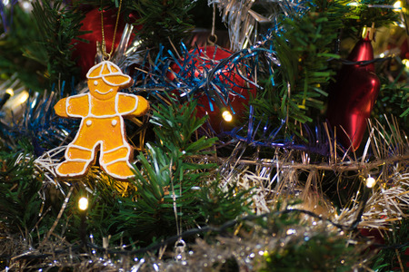 Artificial christmas tree decorated with wooden figurine, decoration for christmas tree, lights, tinsel and garland, red ballsの写真素材