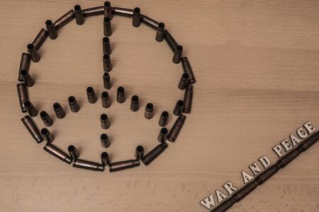 Symbol of peace made from the shells of military rifle with the inscription war and peace in the corner with the letters of the wood.の写真素材