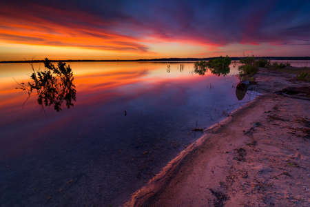 Vivid Texas sunrise over Benbrook Lake with beautiful reflections on the waterの写真素材