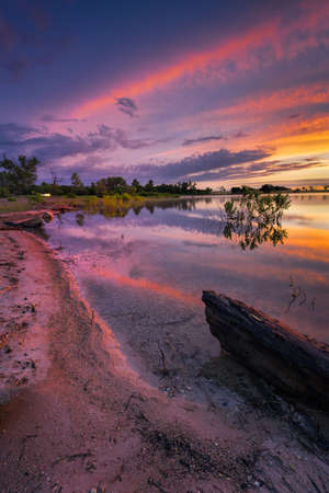 Vivid, multicolored sunrise over Benbrook Lake, Texas with beautiful predawn reflections on the waterの写真素材