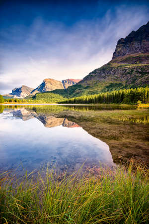 Red rocks, pine trees, and clear reflecting water at Red Rock Lake in Glacier National Park, Montana on a late summer afternoonの写真素材