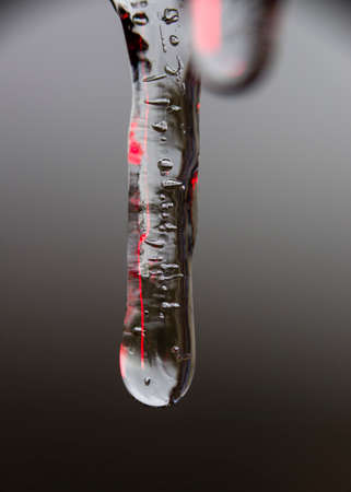Close up view of icicles with internal red reflections on a cool neutral の写真素材