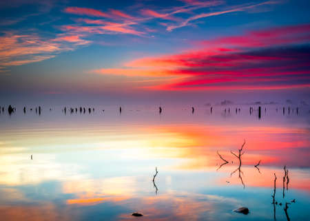 Vivid Texas sunrise over Benbrook Lake with colorful pastel reflections on the calm waterの写真素材