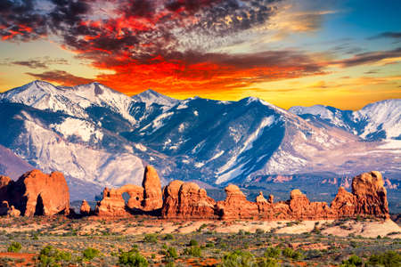 Amazing contrast between the red sandstone hills and the cool Rocky Mountains in the background  as seen in Arches National Park, Utahの写真素材