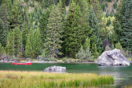 Peaceful summer scene featuring a woman canoeing on Jenny Lake in Grand Teton National Parkの写真素材