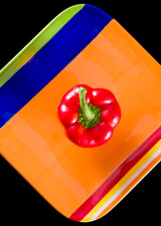 Fresh red bell pepper placed in the middle of a multicolored dishの写真素材