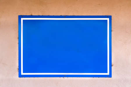 Blue sign with white border hanging on a weathered adobe wall in New Mexicoの写真素材