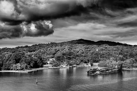 Old whipwrecked vessel under an ominous sky off the coast of Roatan, Hondurasの写真素材