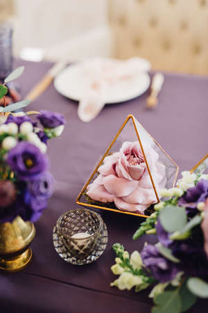Pink and violet flowers in florariums on violet festive table. Wedding decorの写真素材