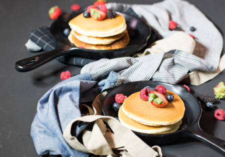 Home made pancakes with berries on metal frying pan decorated with berries (blueberries, raspberries...