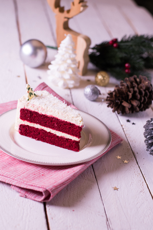 Christmas cake on plate on red fabric on wood background and decorations.の写真素材